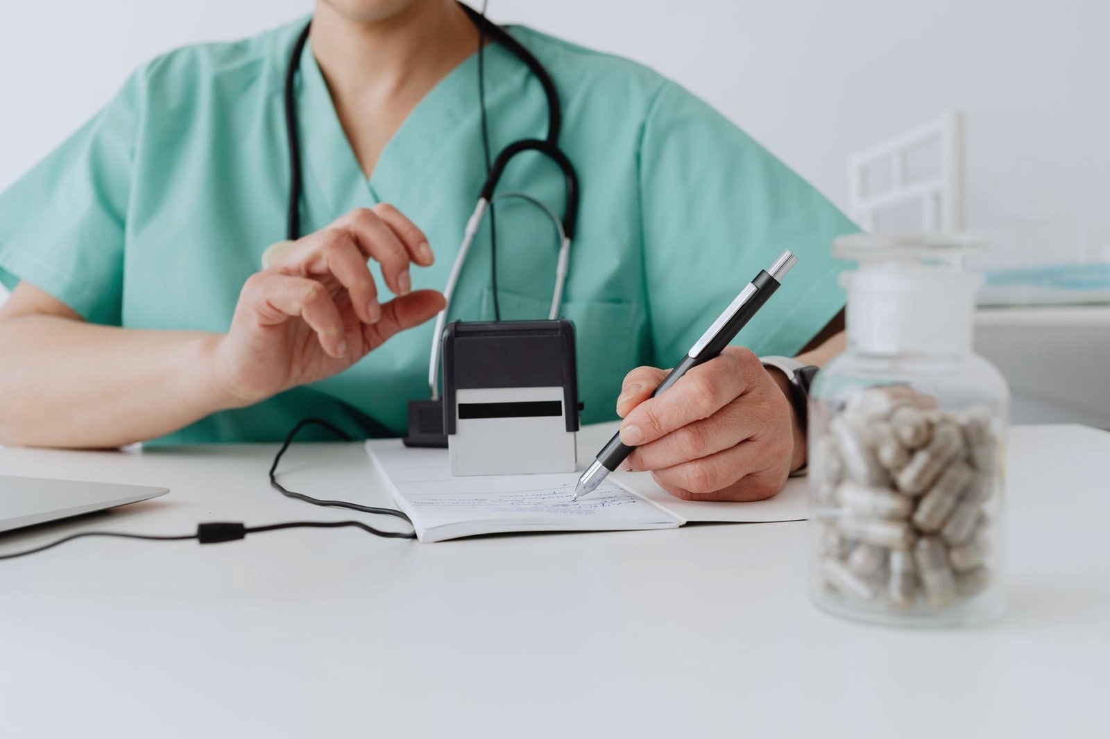 A clinician writing at a desk beside a jar of capsules