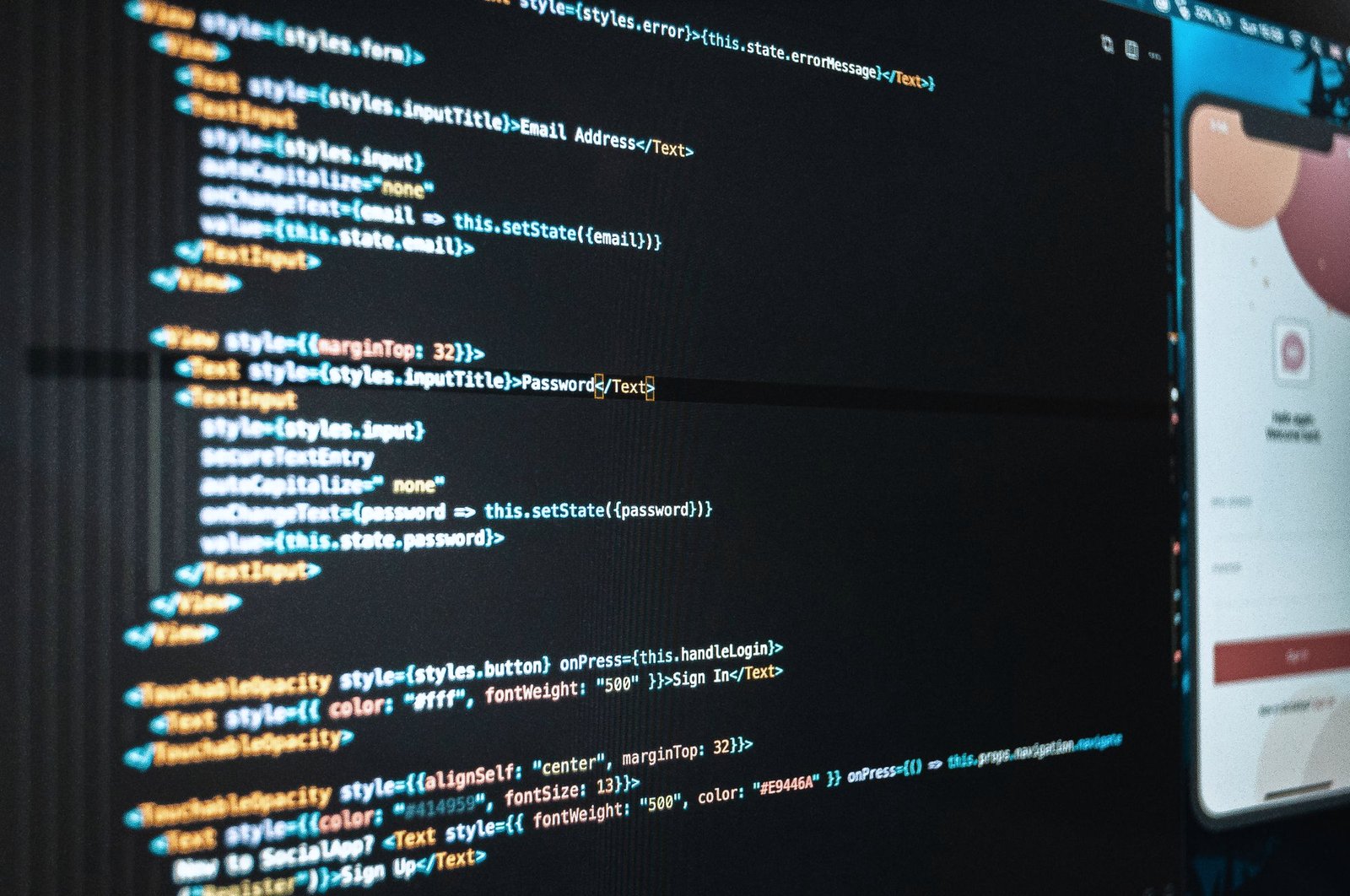 Software code on a laptop screen beside a phone