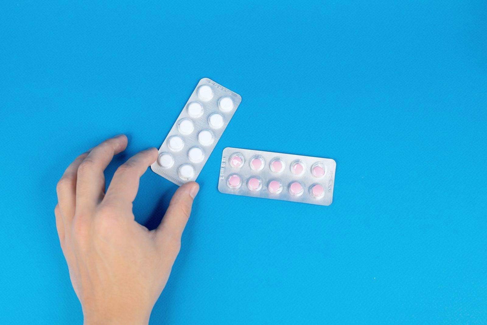 A hand holding a blister pack of tablets