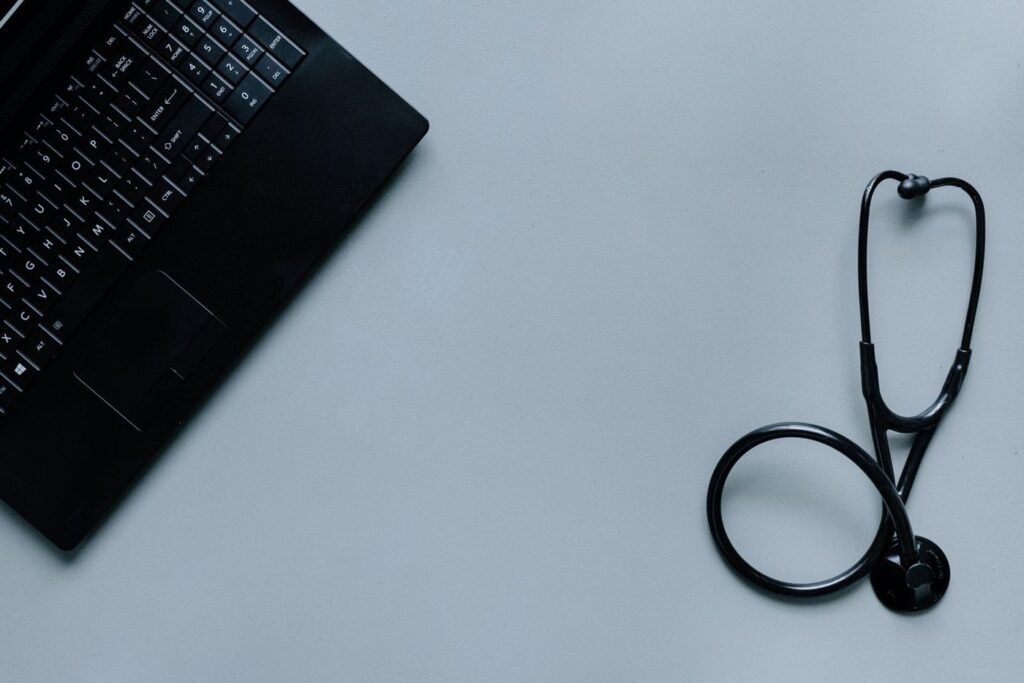 A laptop and stethoscope on a grey desk