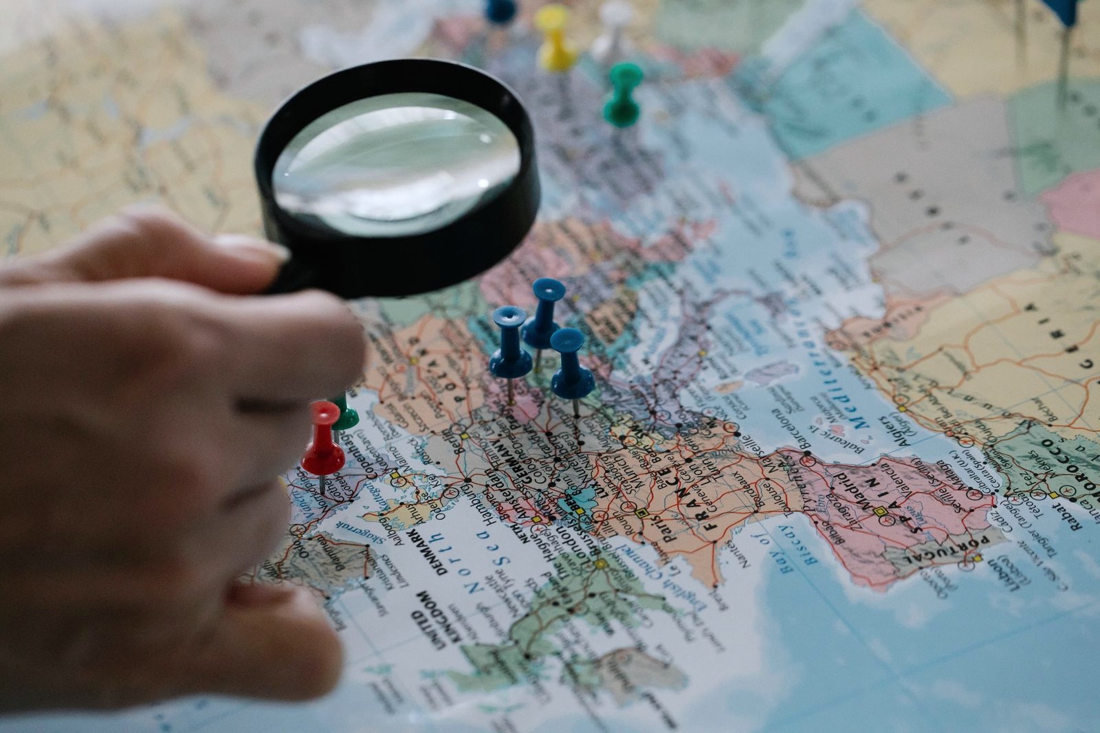 A magnifying glass over a world map with pins