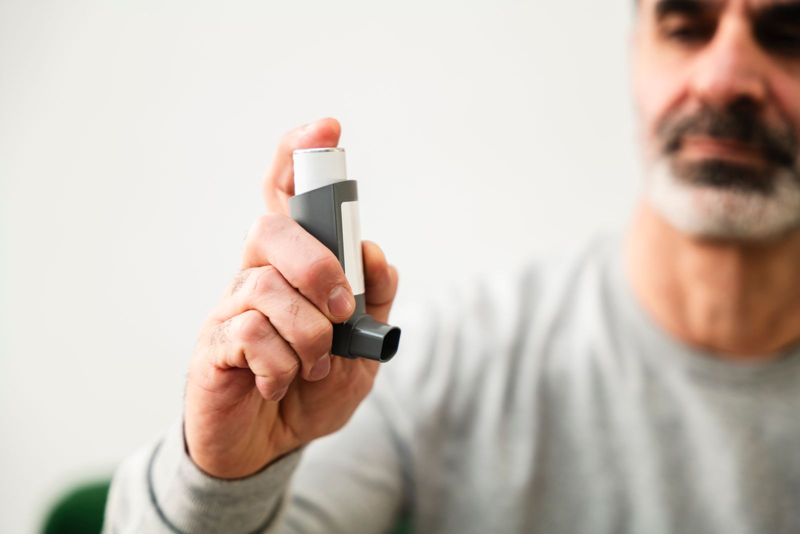 A man holding an asthma inhaler