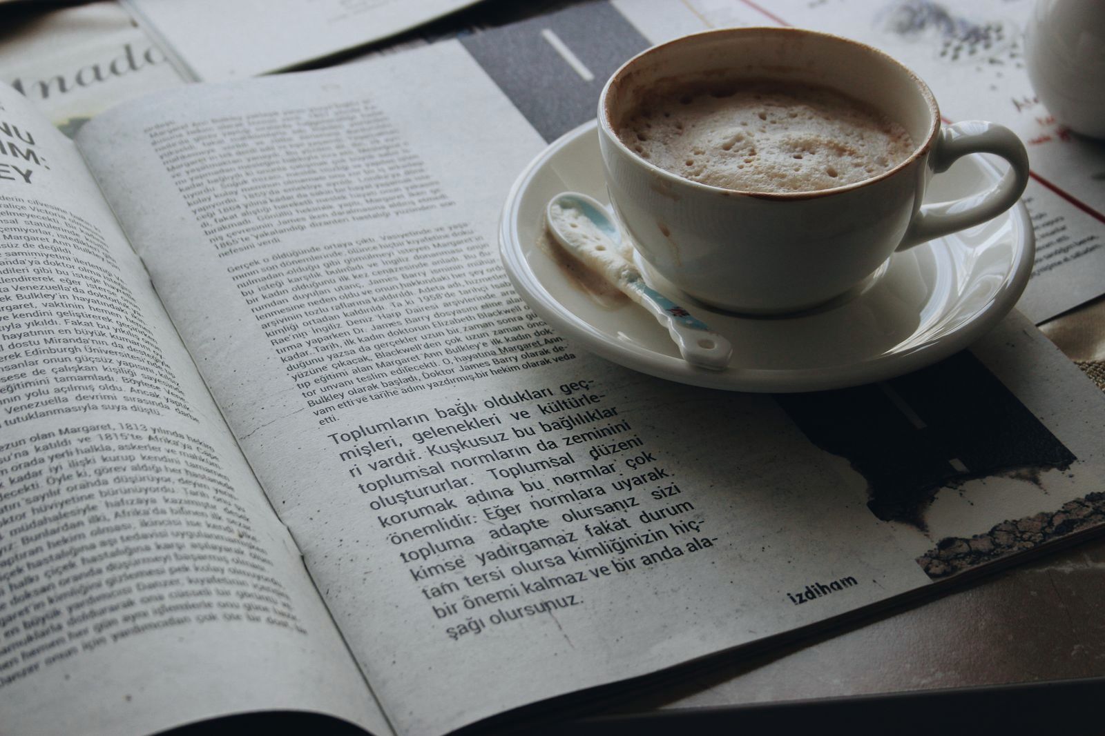 An open newspaper beside a cup of coffee