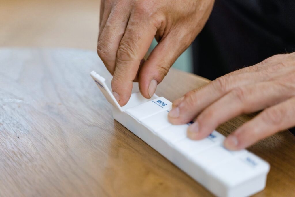 Older hands filling a weekly pill organiser