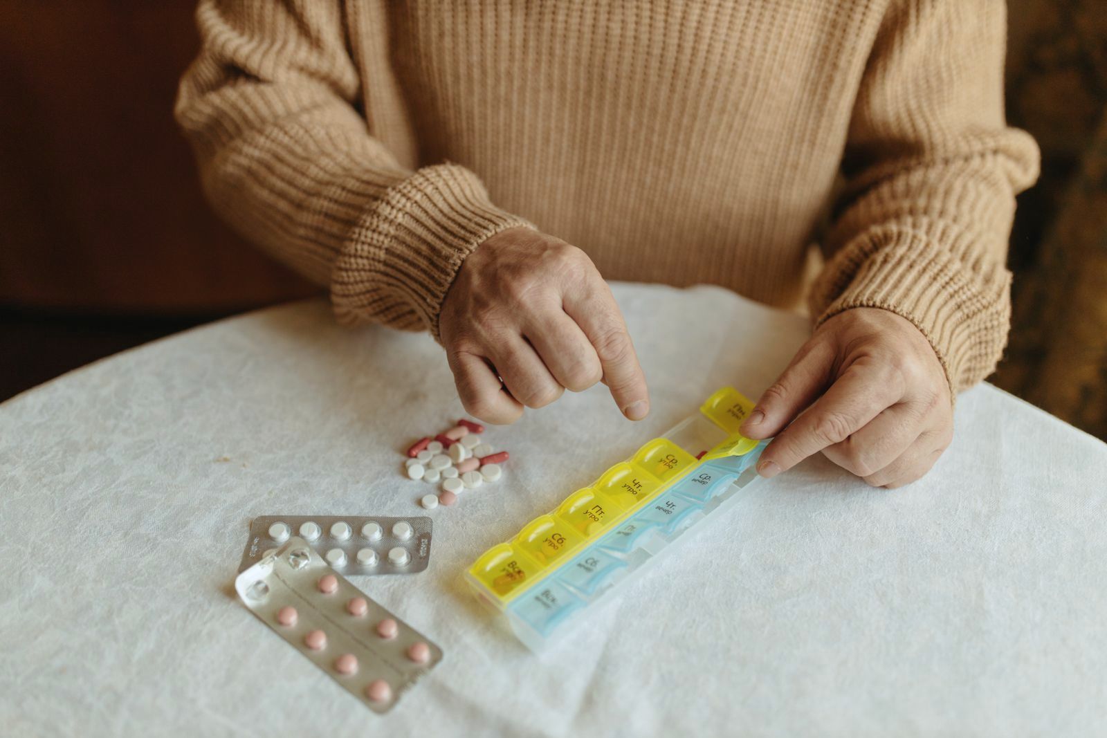 An older woman sorting tablets into a weekly pill organiser